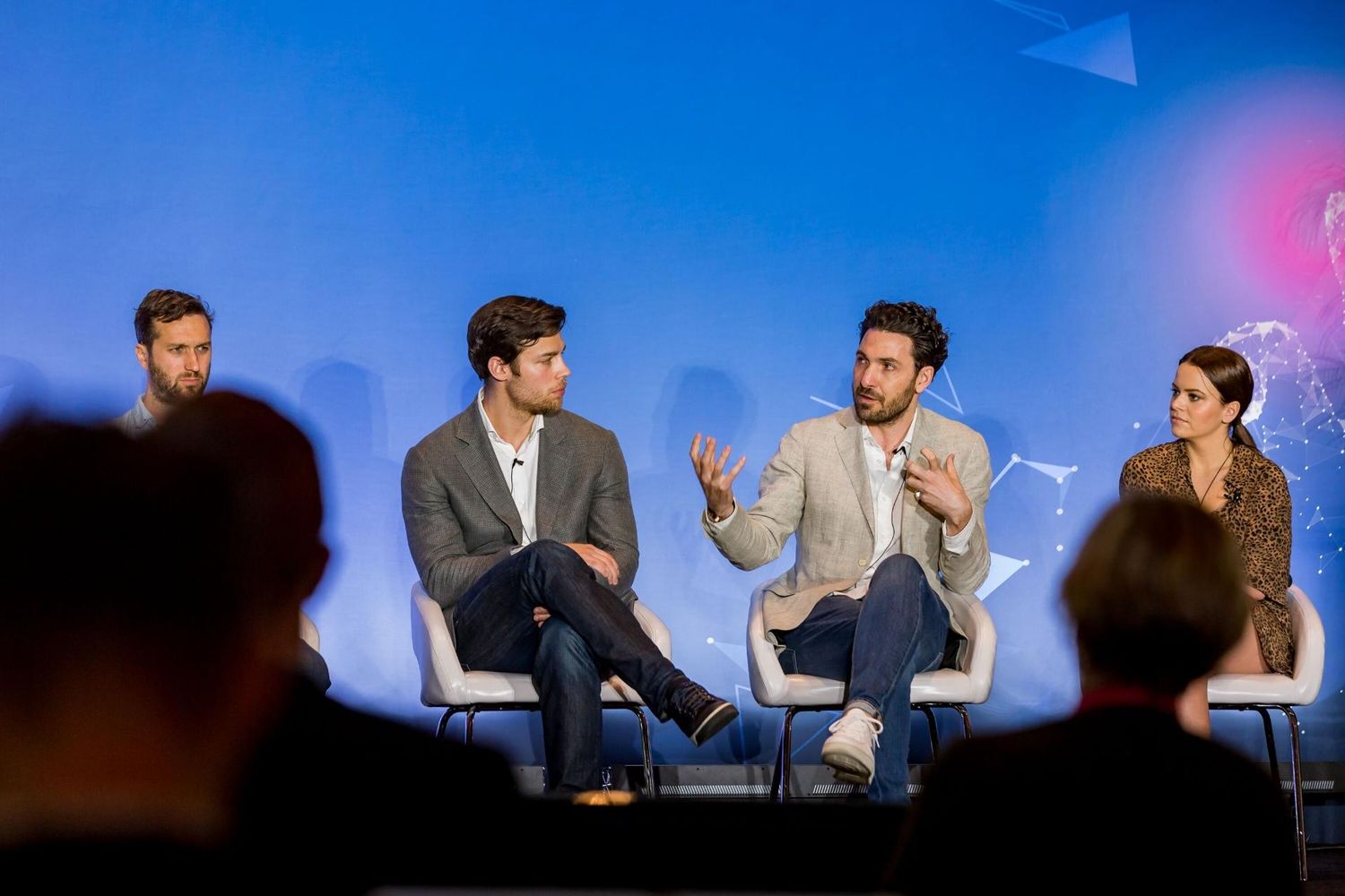 Panel discussion with speakers seated on stage at business conference.