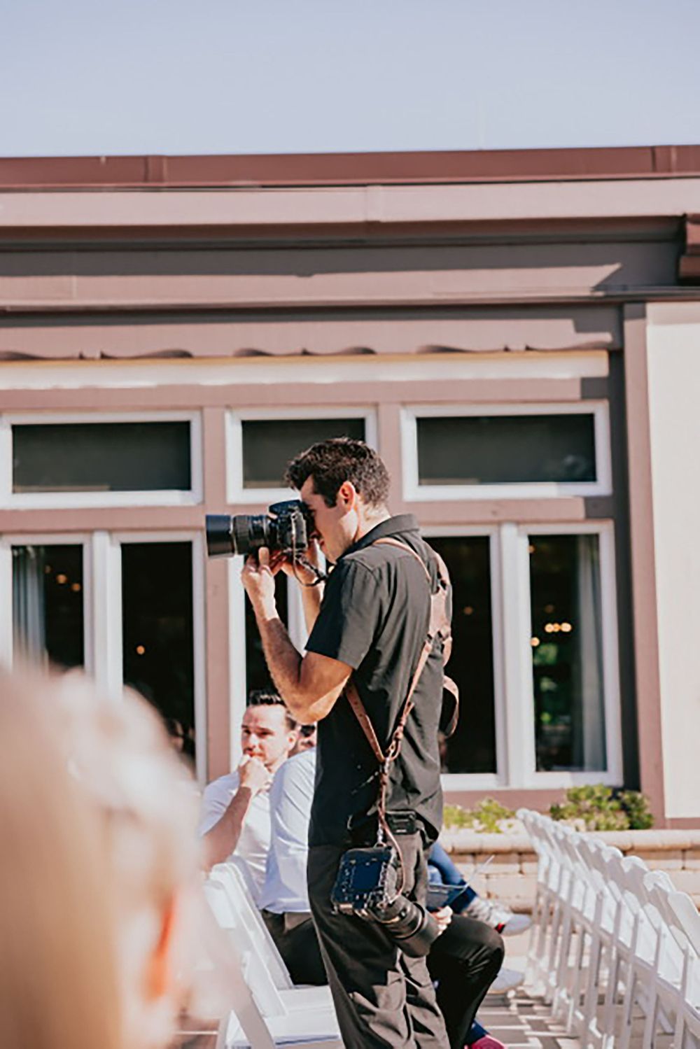 A photographer with professional gear captures shots during an outdoor wedding ceremony.