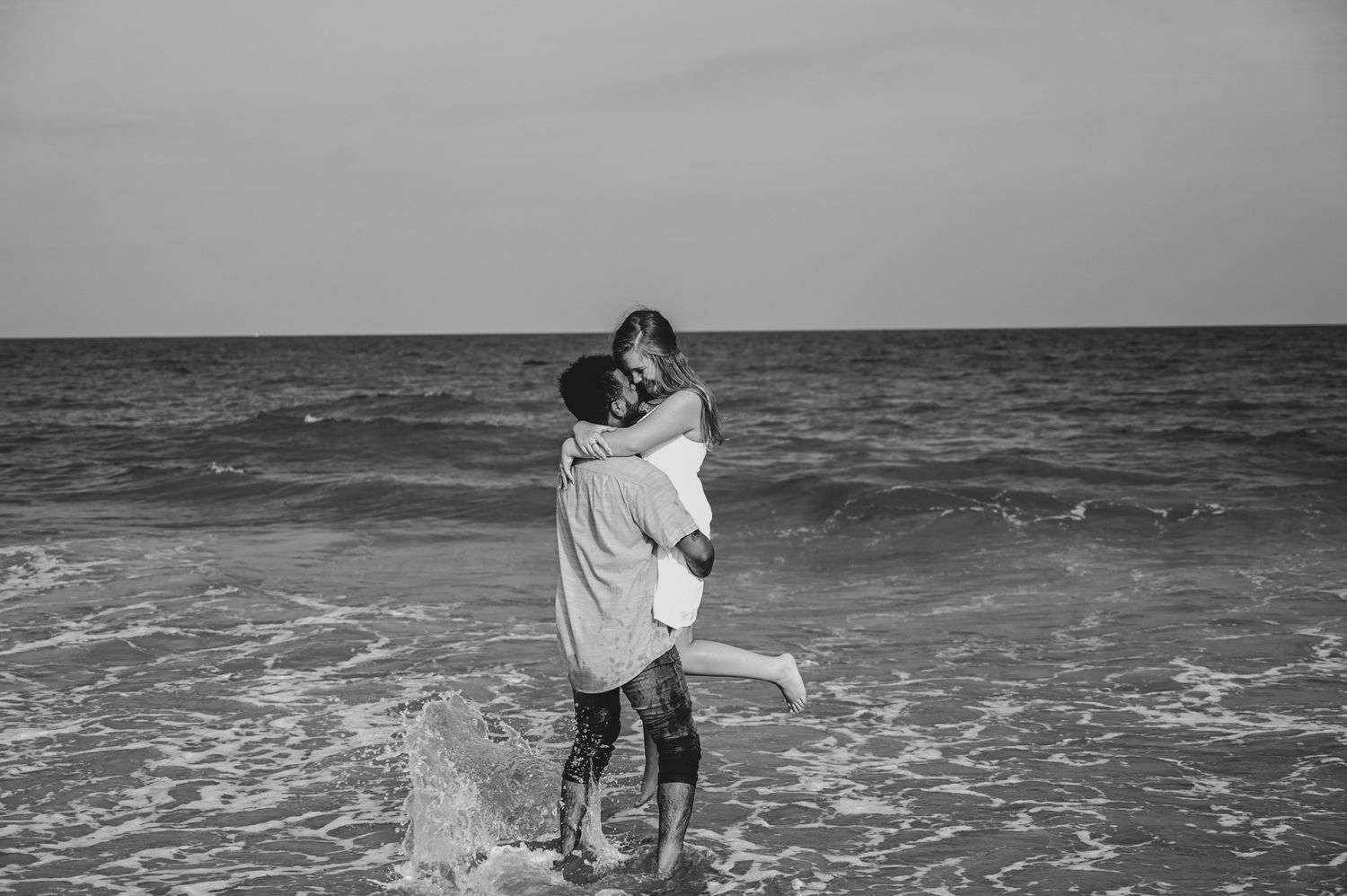 Couple playing and splashing in ocean waves at the beach.