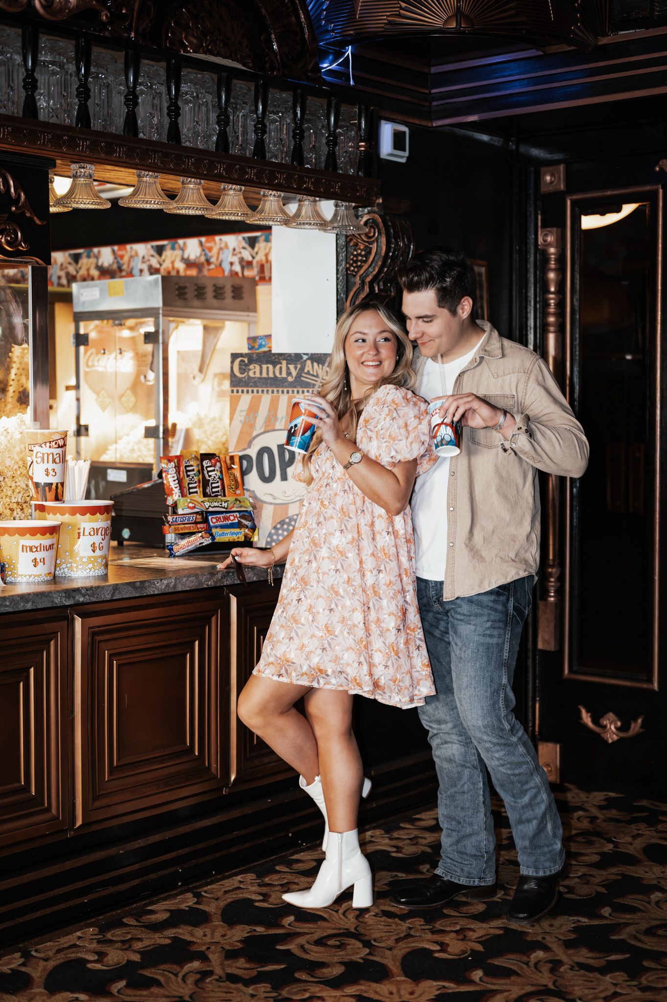 A couple in coordinated outfits sharing a playful moment near a vintage concession stand.