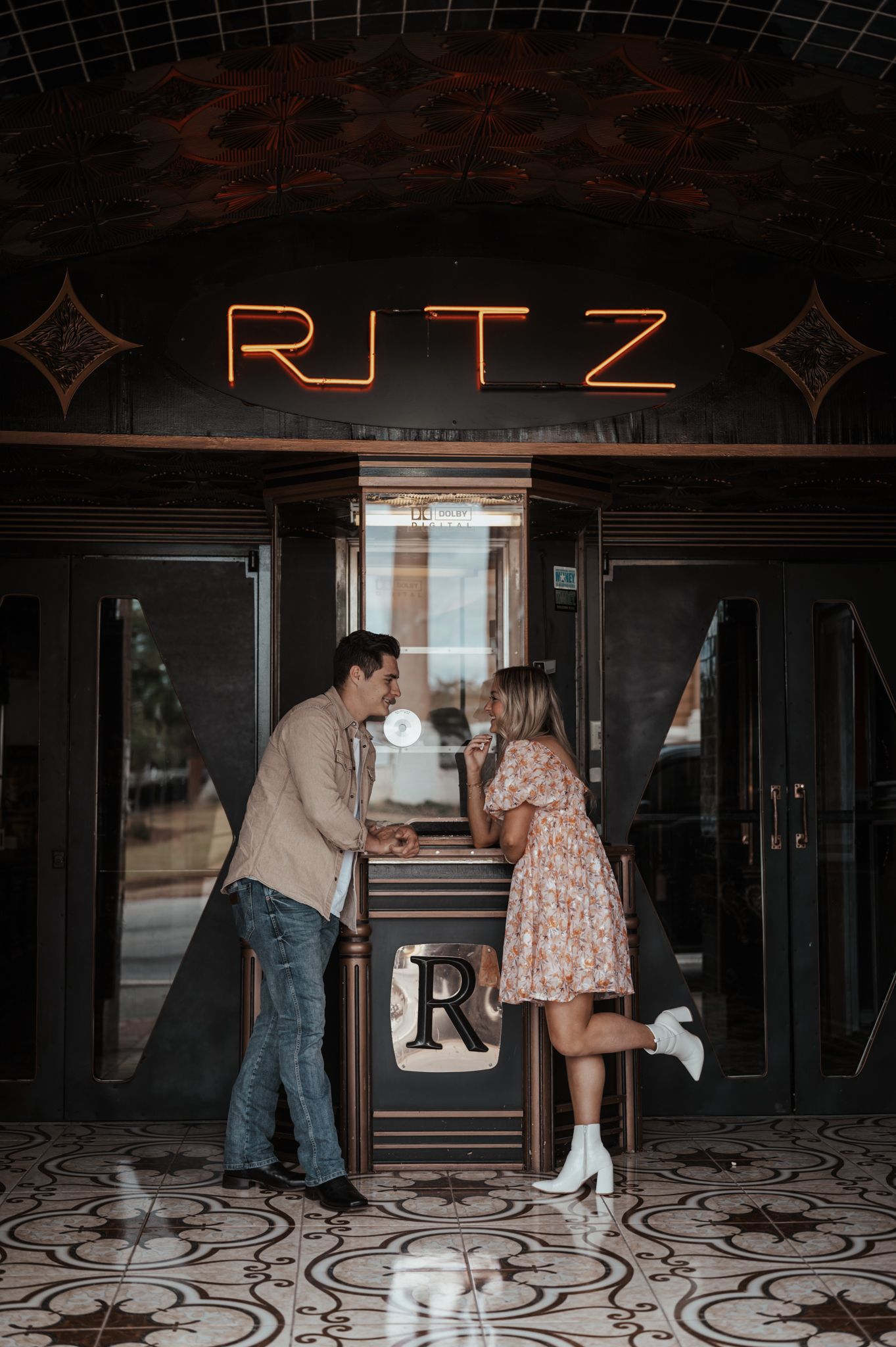 A couple sharing a romantic moment at the entrance of the Ritz theater with vintage neon signage.