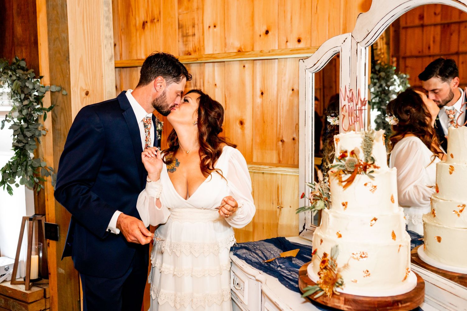 Newlyweds share romantic first dance moments in a rustic wooden barn venue with warm lighting.