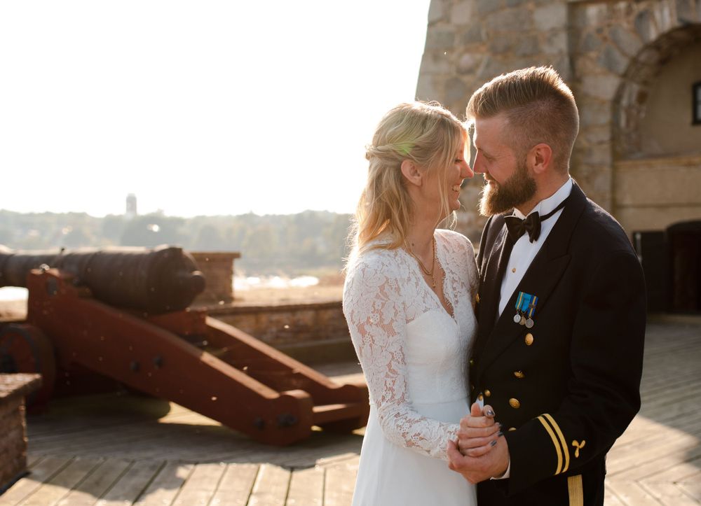 Intimate wedding portrait against historic stone architecture and rustic cannons.