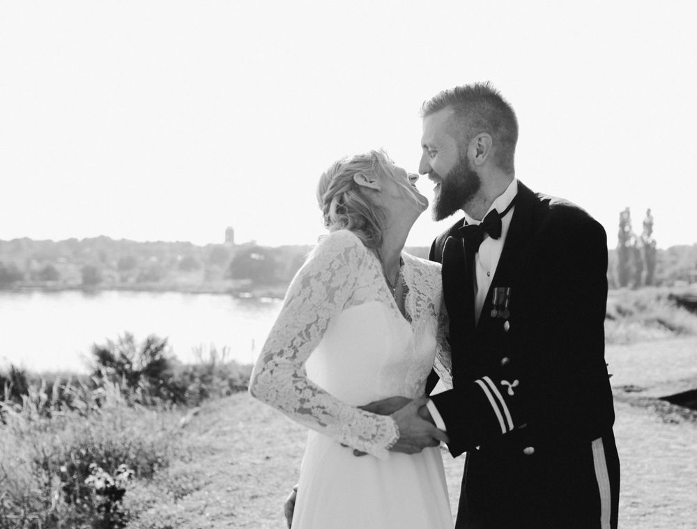 Black and white wedding portrait with a scenic waterfront backdrop.