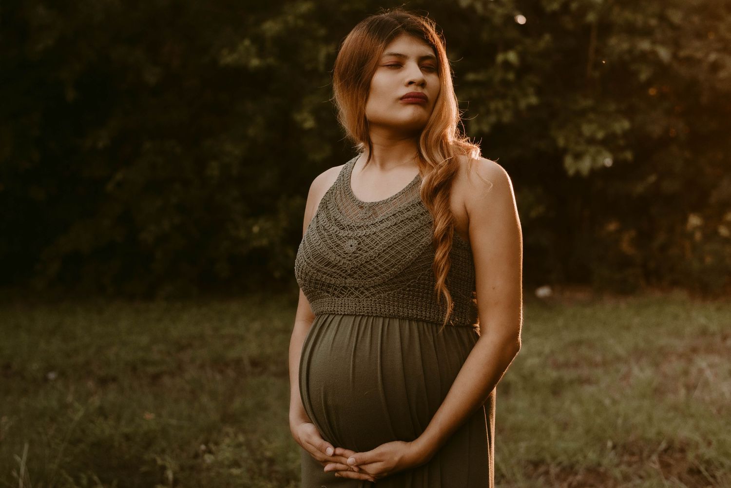 Maternity portrait with textured bodice dress in warm evening light.