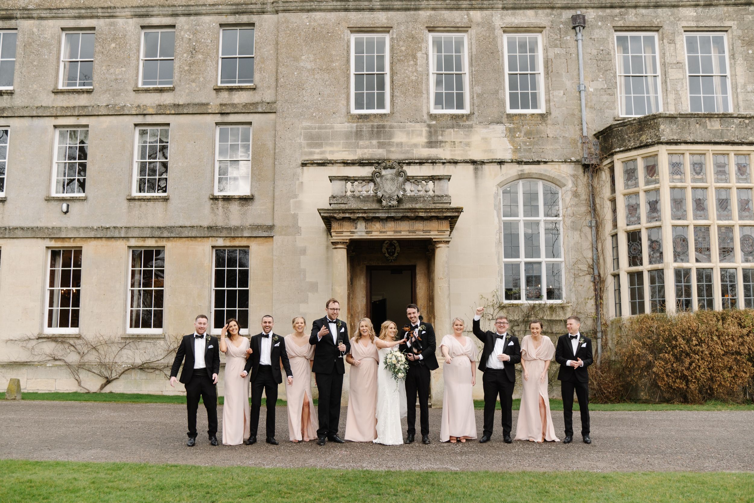 Bride and groom with their sausage dog, bridesmaids and groomsmen in front of Elmore Court