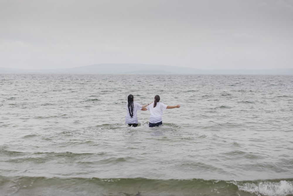 two woman running in the sea with their clothes still on