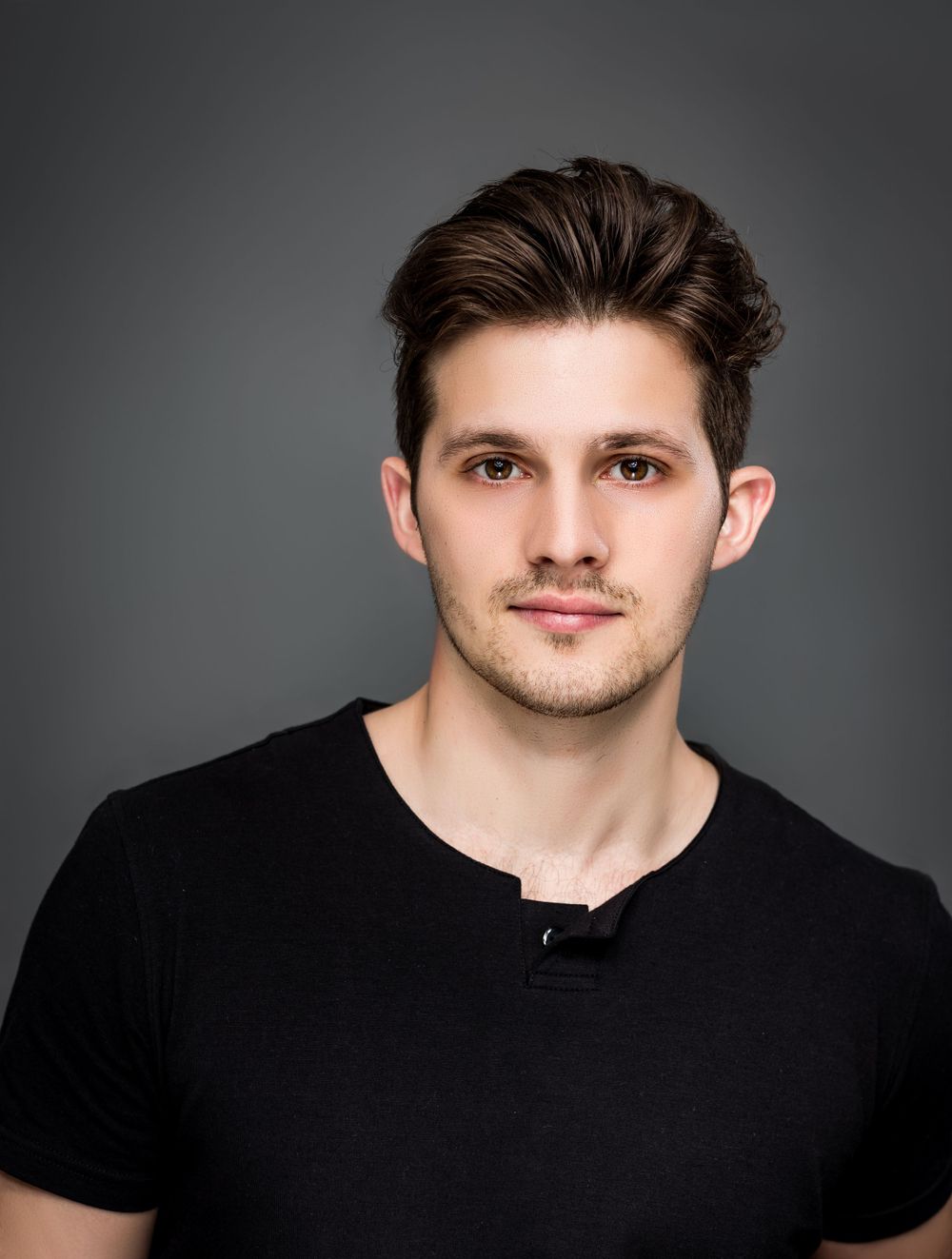 Studio portrait of a young model wearing a black t-shirt against a dark background.