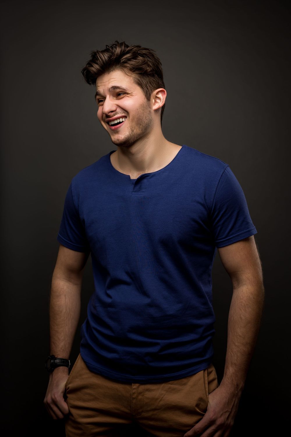 Casual portrait of a person wearing navy t-shirt and khakis against dark backdrop.