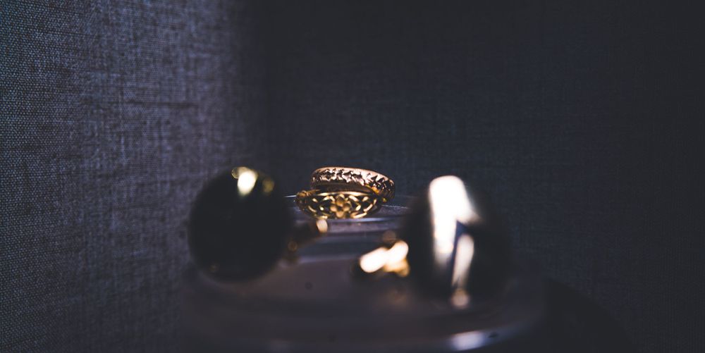 Close-up of ornate wedding ring with dramatic lighting and dark background.