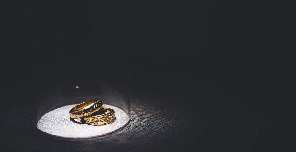 Wedding rings photographed in dramatic spotlight on white surface.