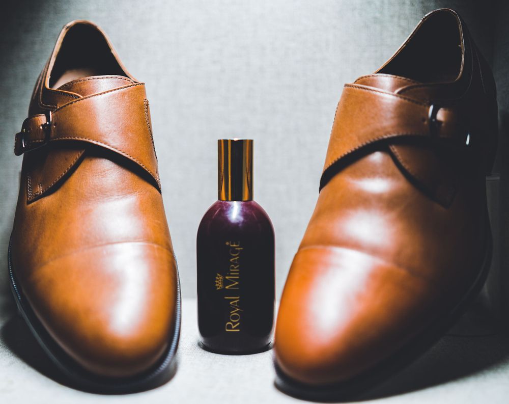 Elegant brown leather dress shoes displayed with a bottle of men's cologne.