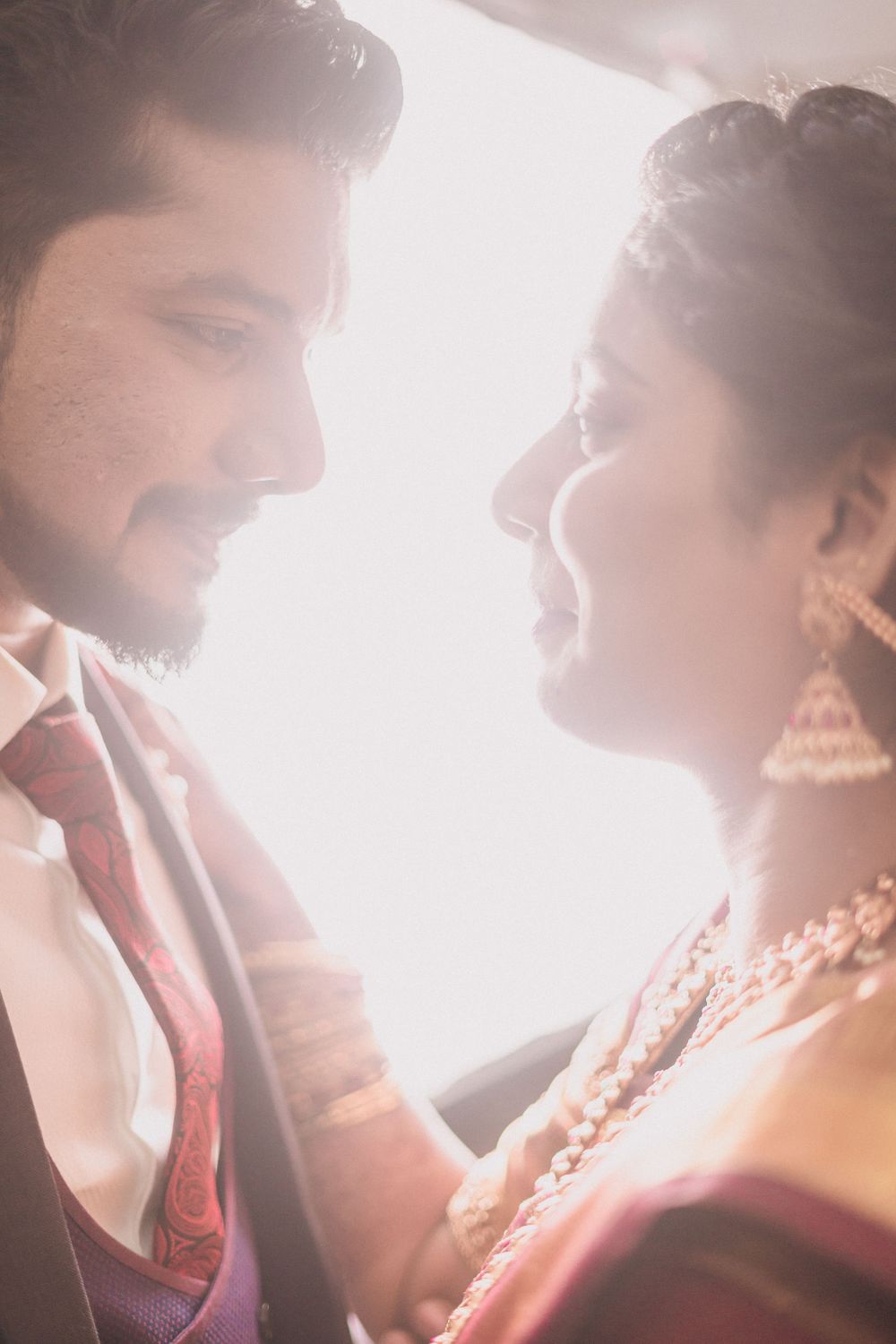 Close-up wedding portrait with dreamy backlighting showing tender moment between newlyweds.