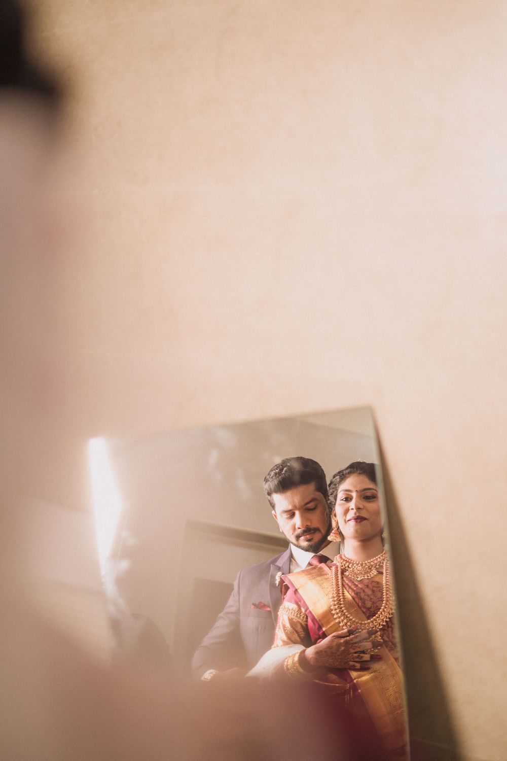 Artistic mirror reflection of newlyweds in traditional Indian wedding attire.