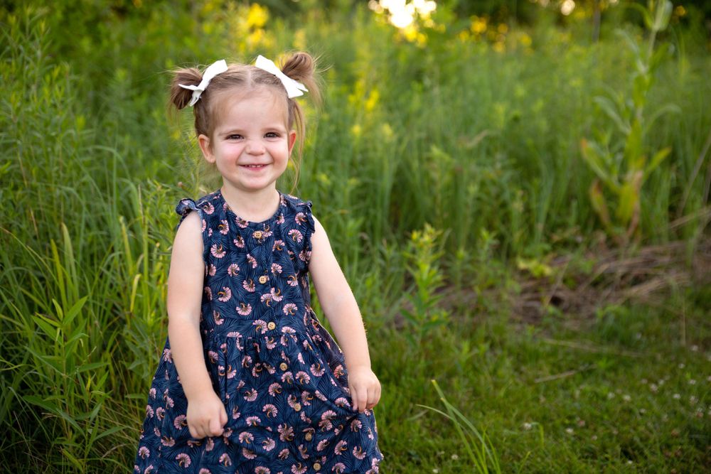 Little girl smiles in a field of green grasses at sunset in Dublin Ohio
