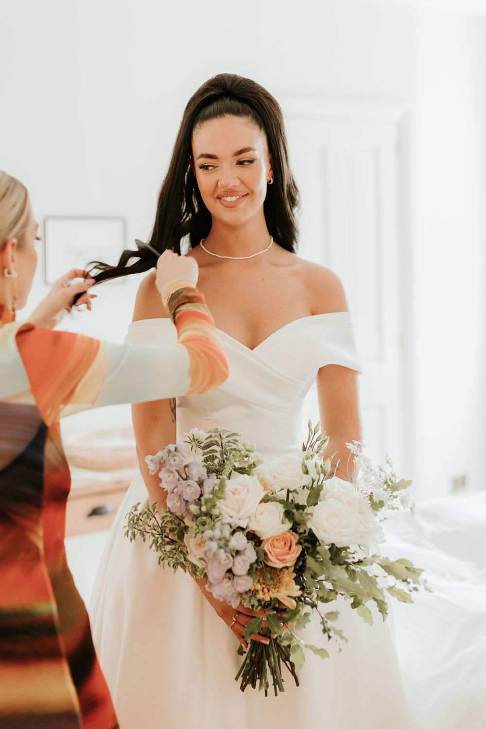 A classic bridal portrait featuring an off-shoulder gown and mixed floral bouquet.