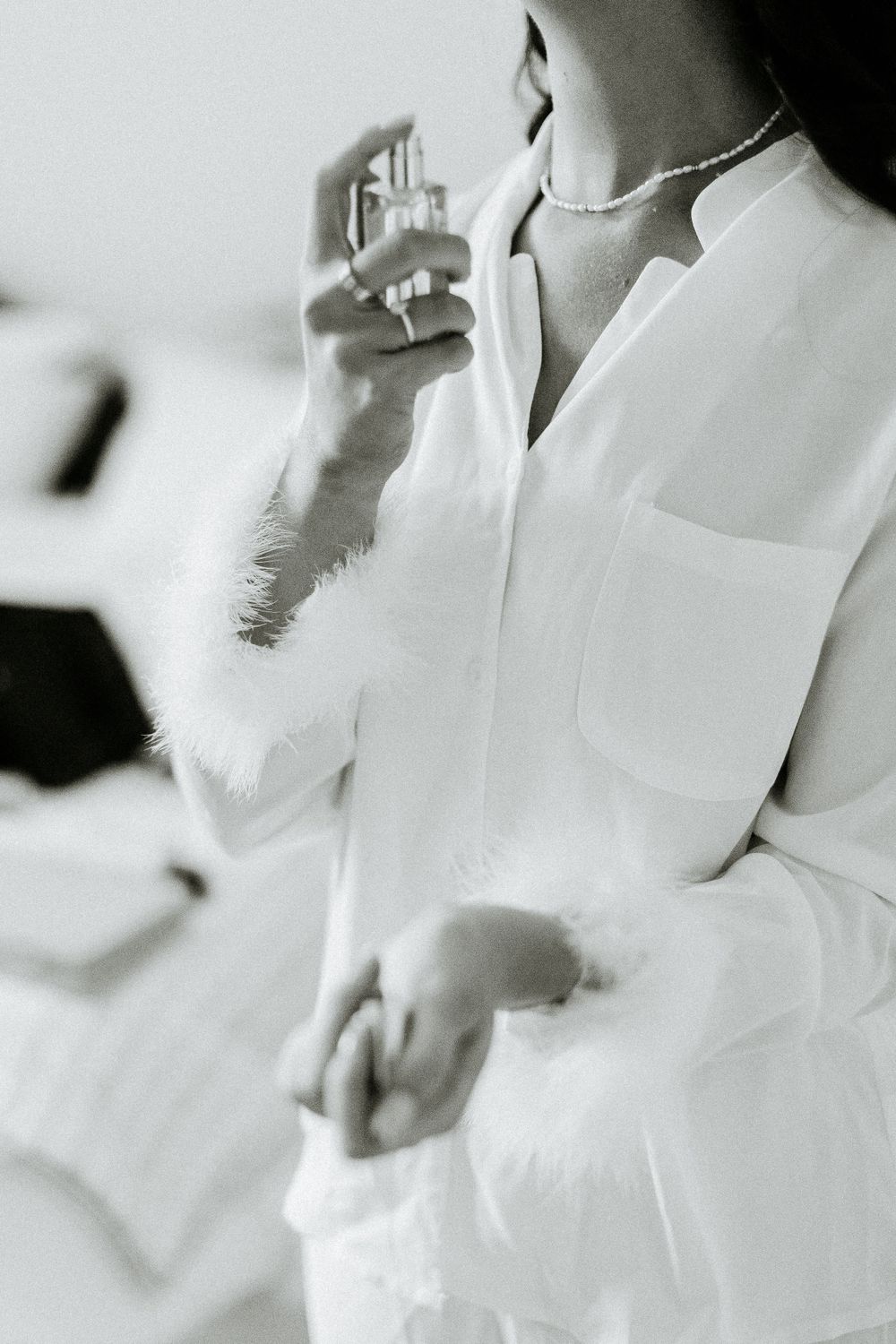 Black and white photo of someone in a white shirt spraying perfume.