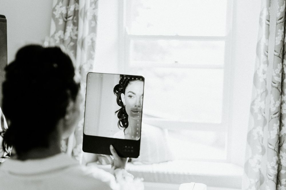 Artistic black and white reflection of someone getting ready in a handheld mirror.