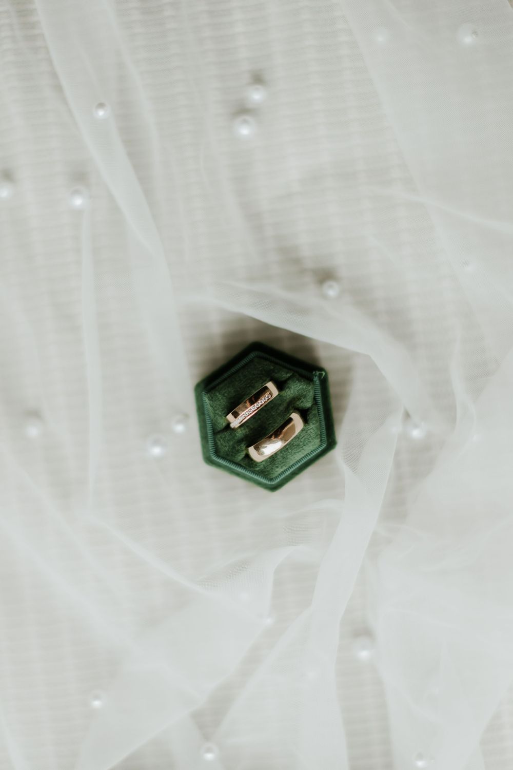 Close-up of an emerald green hexagonal jewelry piece resting on white tulle fabric.