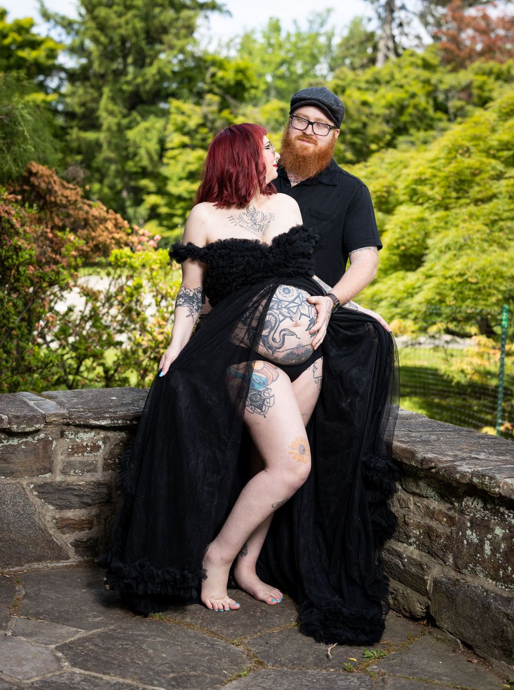 Romantic gothic photoshoot on stone wall surrounded by lush garden.