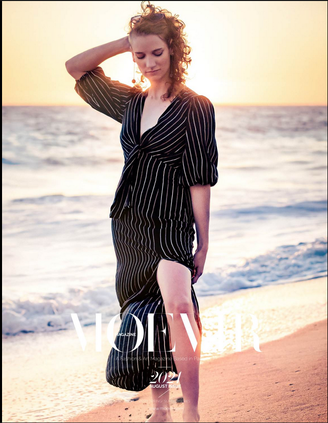 Model poses on coastal rocks in striped dress under golden hour light for a summer fashion editorial. Captured by Chris Cornish Photography.
