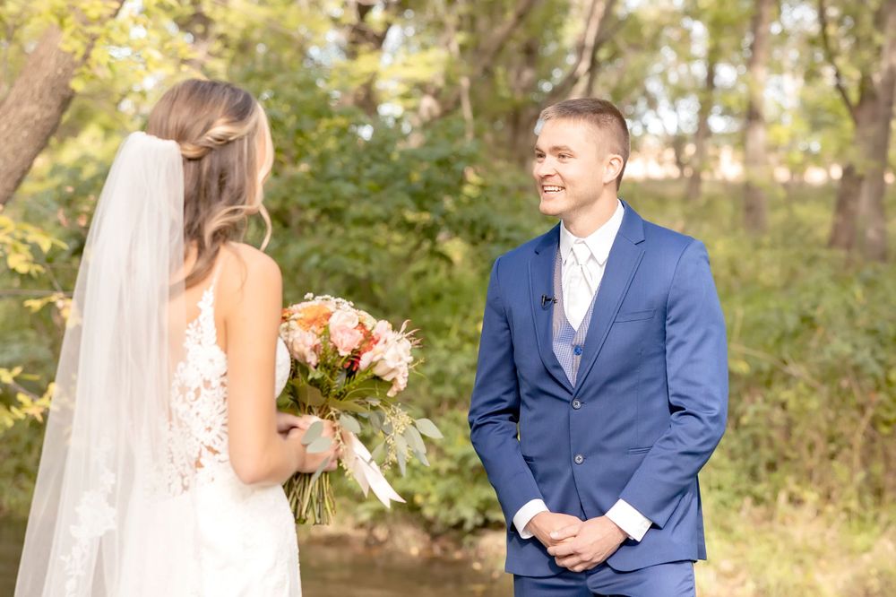 Wedding couple walking hand in hand through a garden setting.