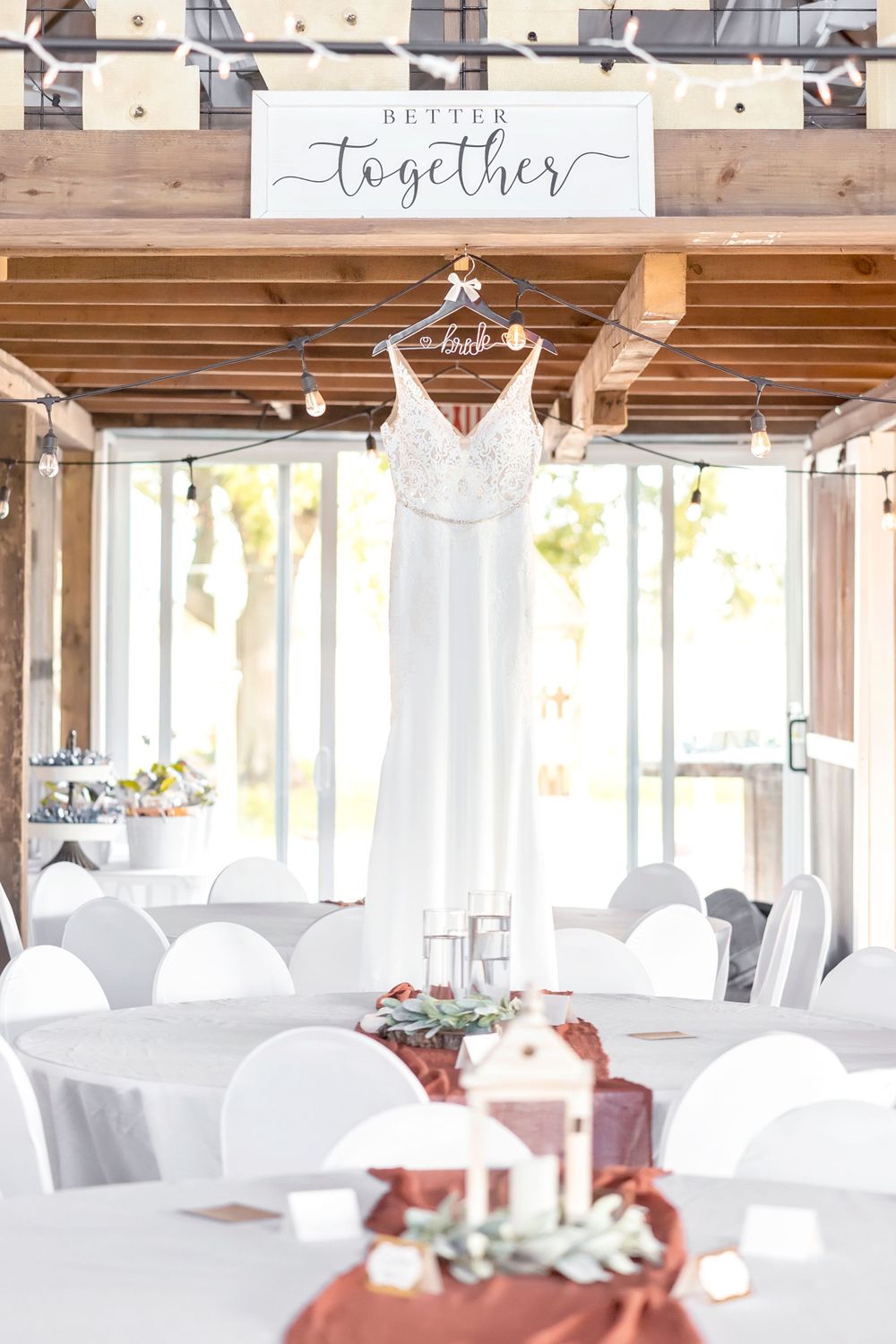 Elegant white wedding reception venue with rustic wooden beams and romantic lighting.