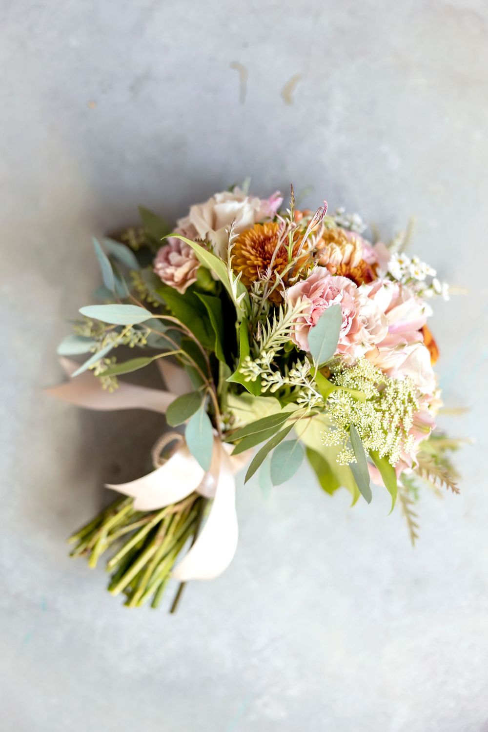 Romantic bridal bouquet with pink flowers, greenery, and delicate foliage.