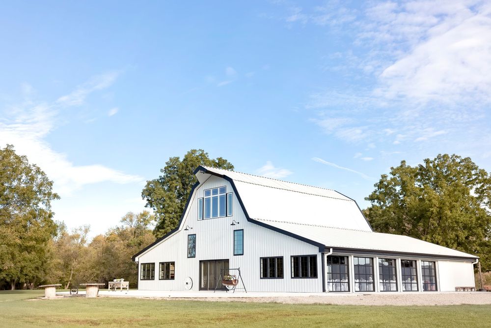 Panoramic view of white modern barn wedding venues under blue sky.