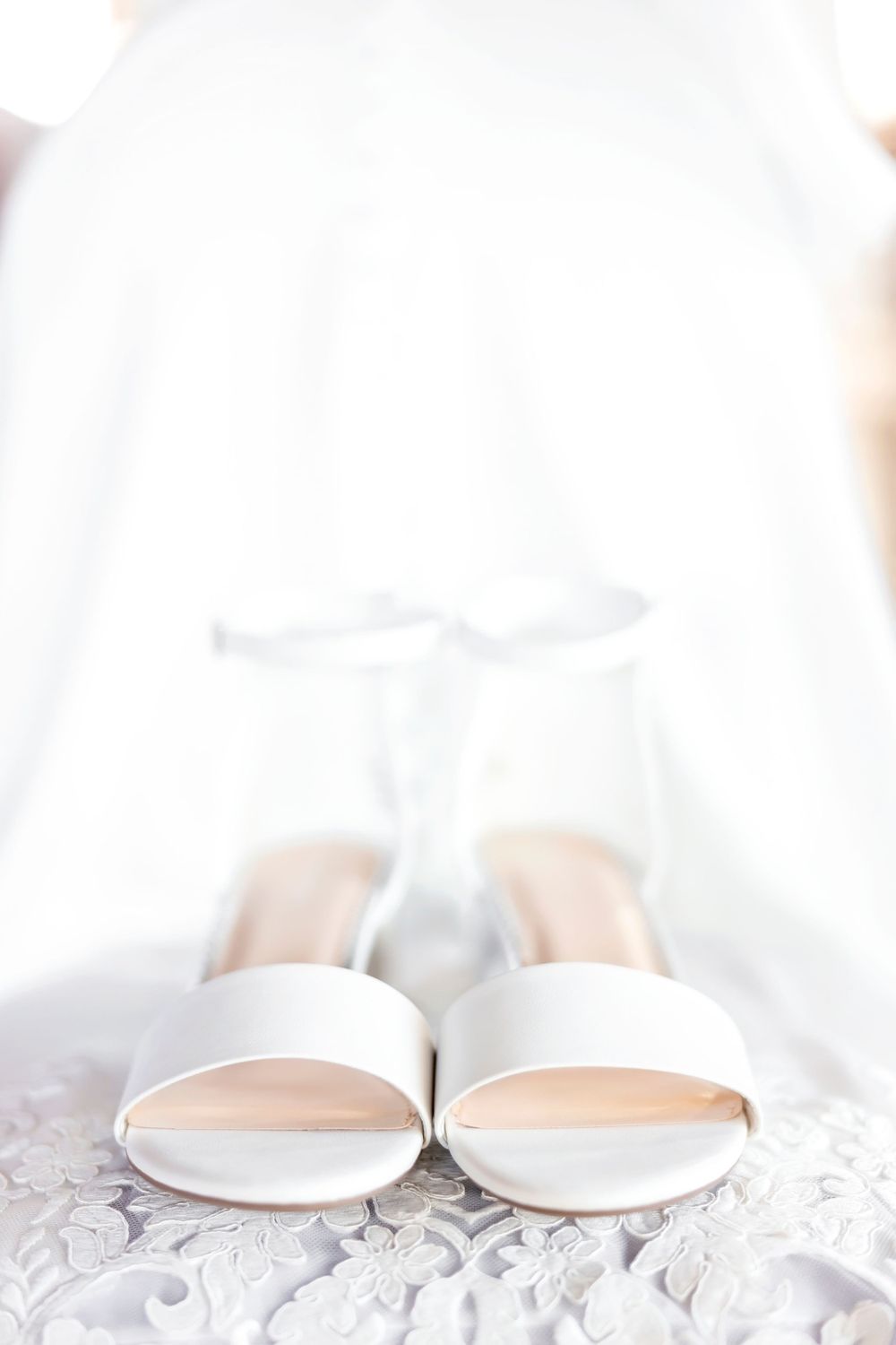 White bridal shoes arranged on lace background with soft lighting.