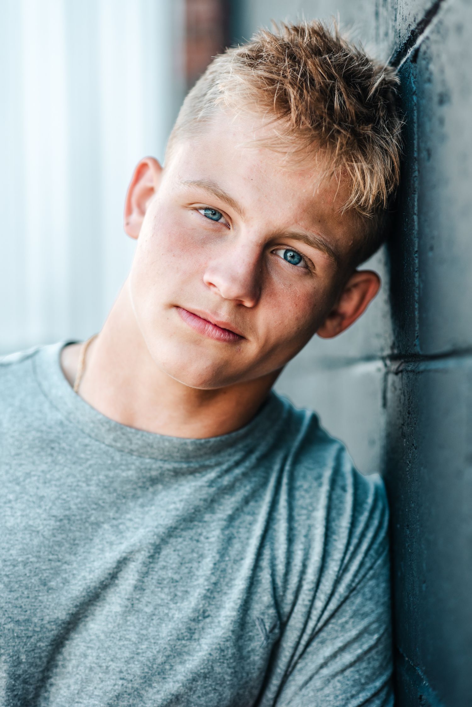 Portrait of student athlete in grey t-shirt against wall.