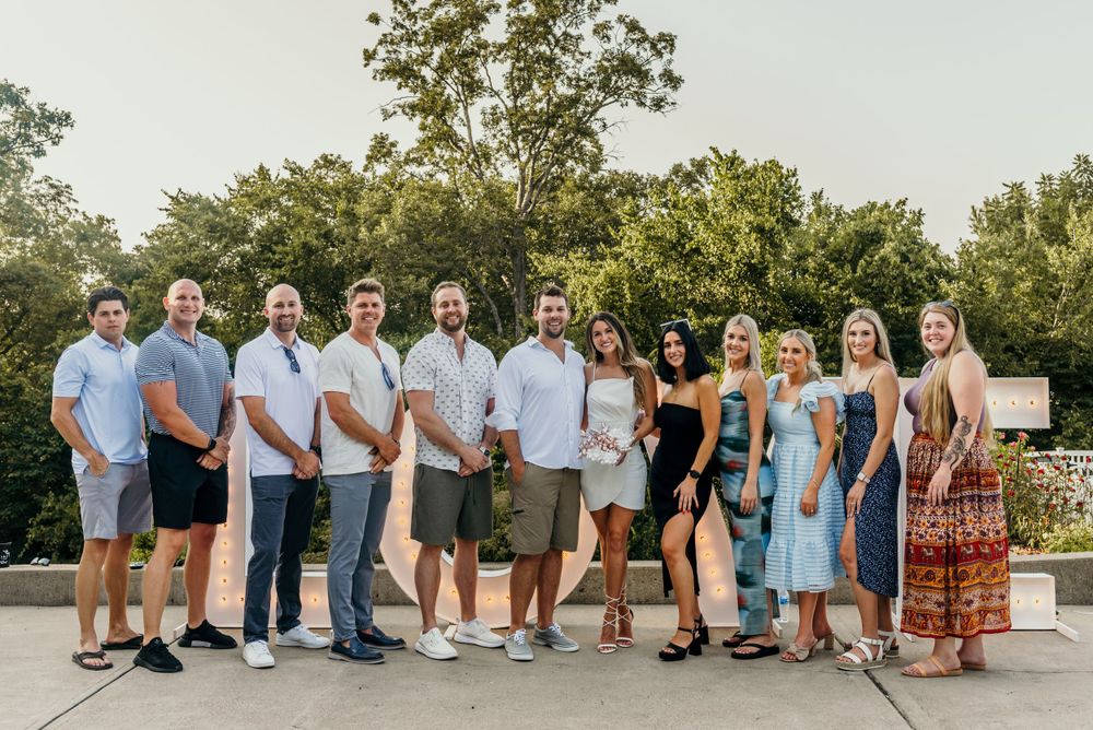 Large group photo arrangement outdoors with coordinated blue and white attire.