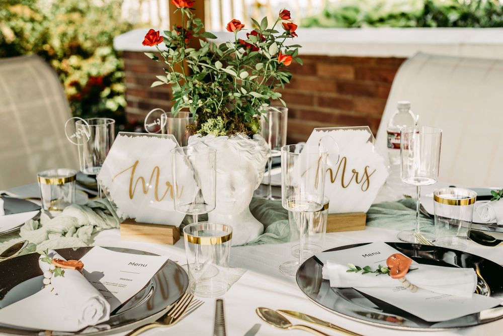Wedding reception table settings with sage green accents and elegant gold details.
