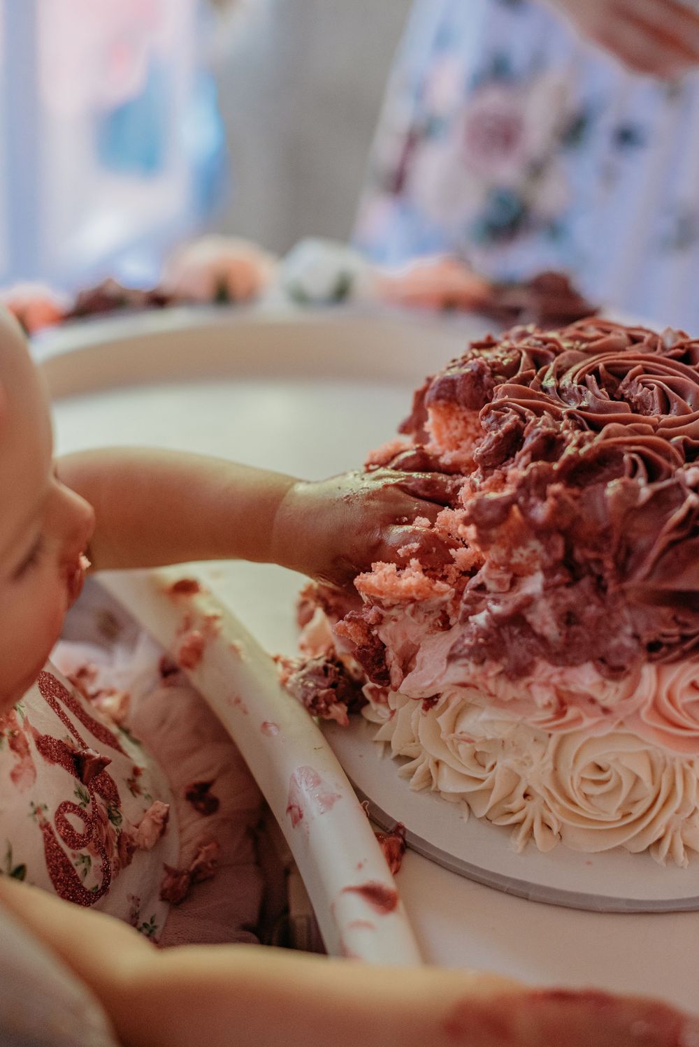 Close-up of an elegantly decorated cake with pink frosting swirls and details.