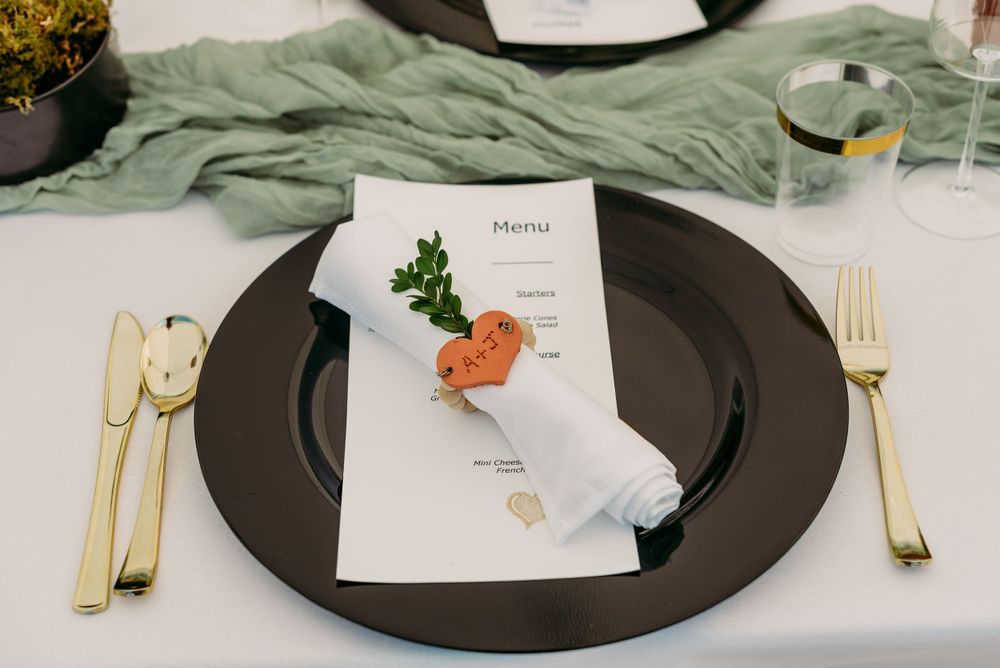Wedding reception table with sage green runner and modern place settings.