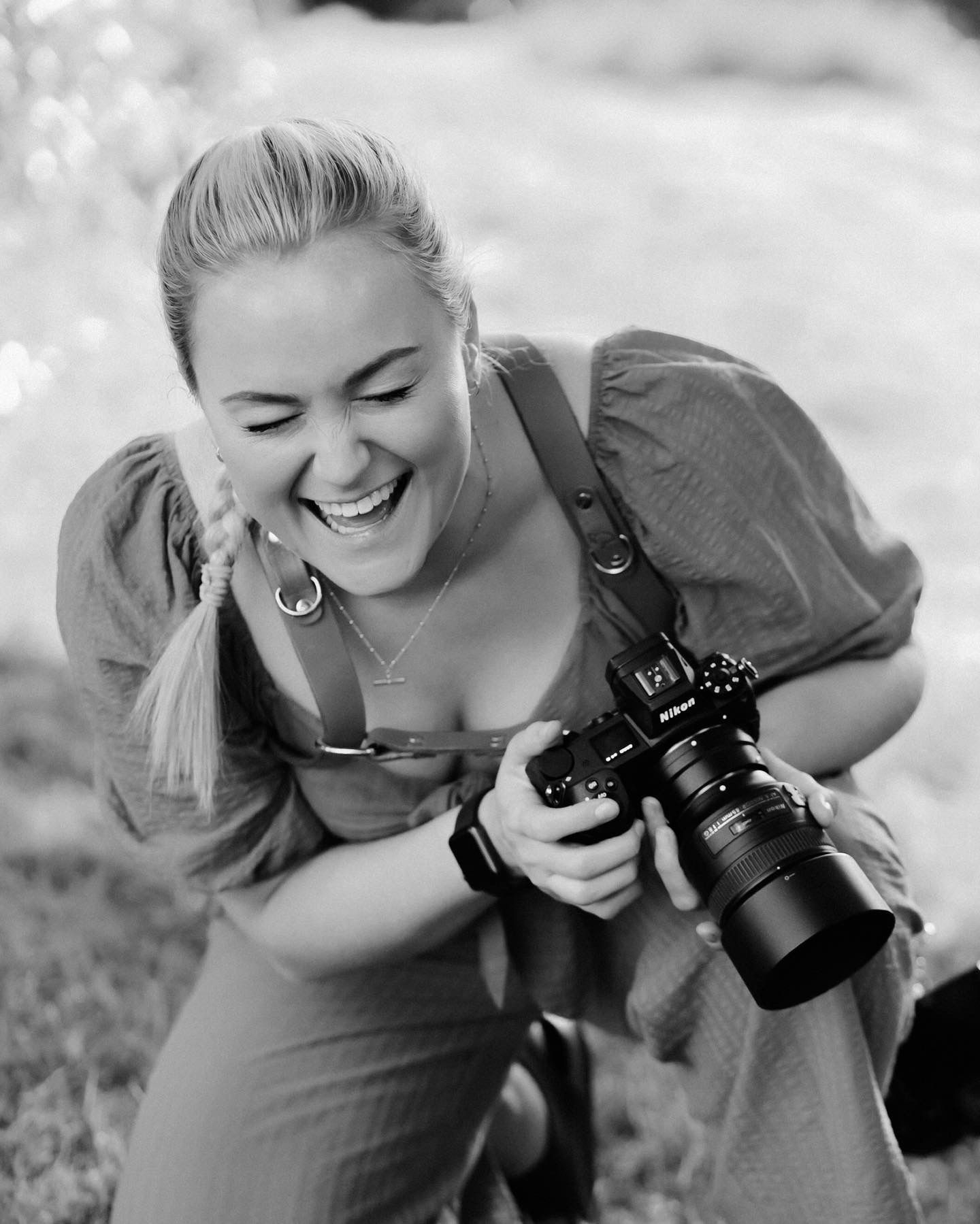 Photographer wearing puff sleeve dress joyfully takes pictures with professional camera outdoors.