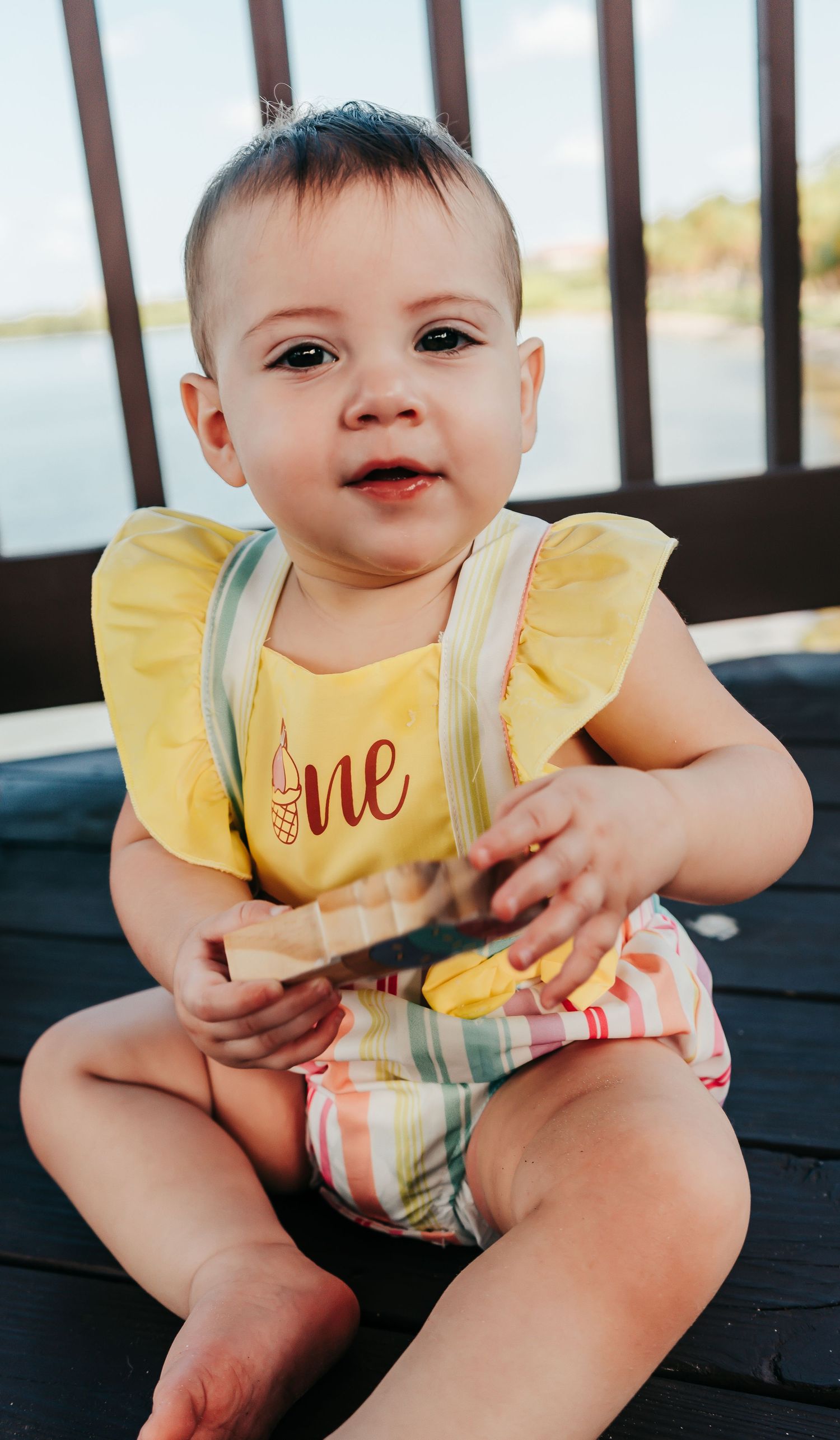 Outdoor Cake Smash Session at Maximo Park in St. Pete, FL; baby holding wooden toy and smiling