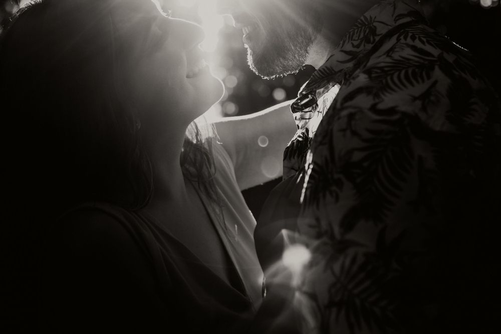 Romantic black and white close-up of couple sharing intimate moment with dramatic light and shadow.