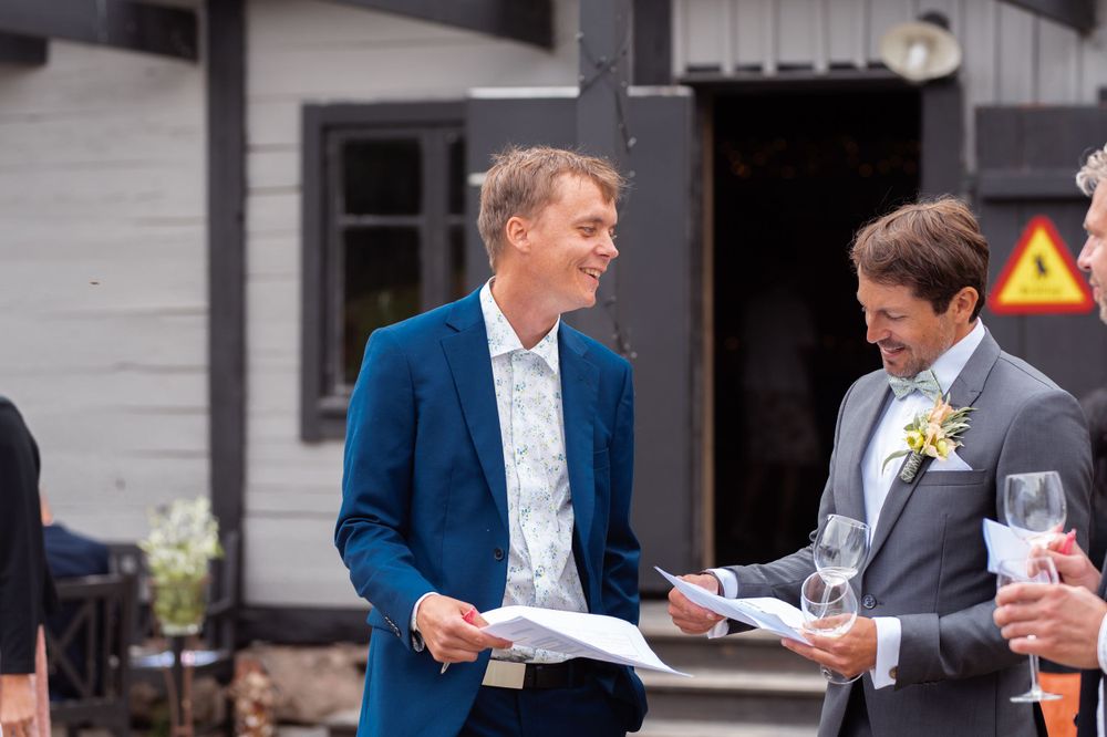 Two people in formal attire reviewing documents outside a building.