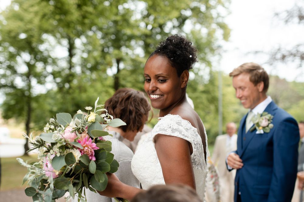 Wedding guests share a candid moment while holding elegant floral bouquets.
