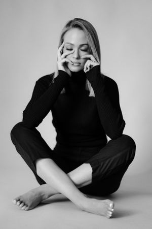 Expressive black and white portrait showing joyful moment in dark sweater against light background.
