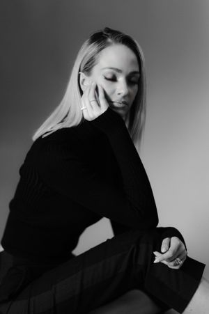 Artistic black and white portrait of a woman in black turtleneck looking down thoughtfully.