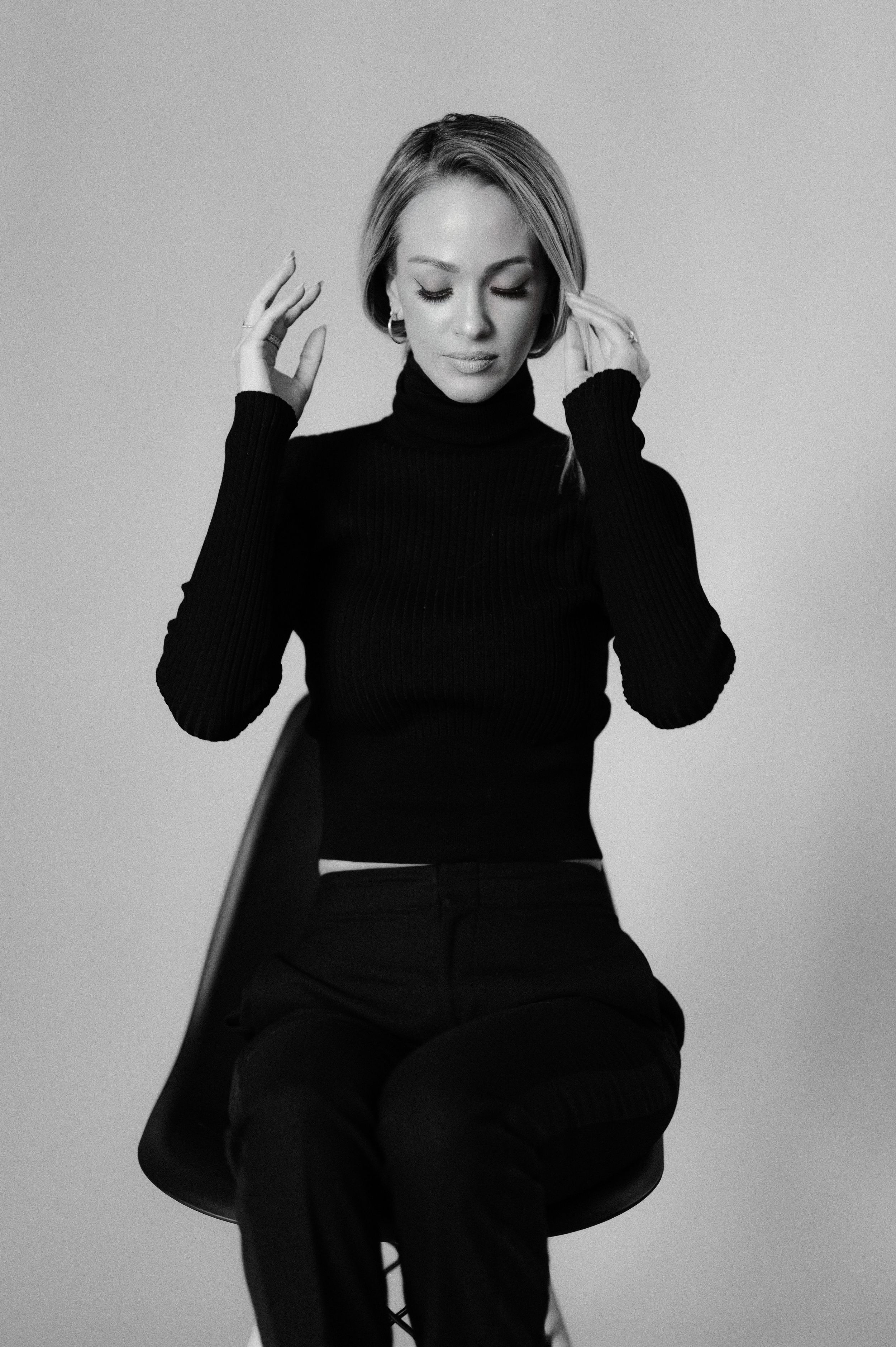 Candid black and white photo capturing emotive moment in dark turtleneck against light backdrop.