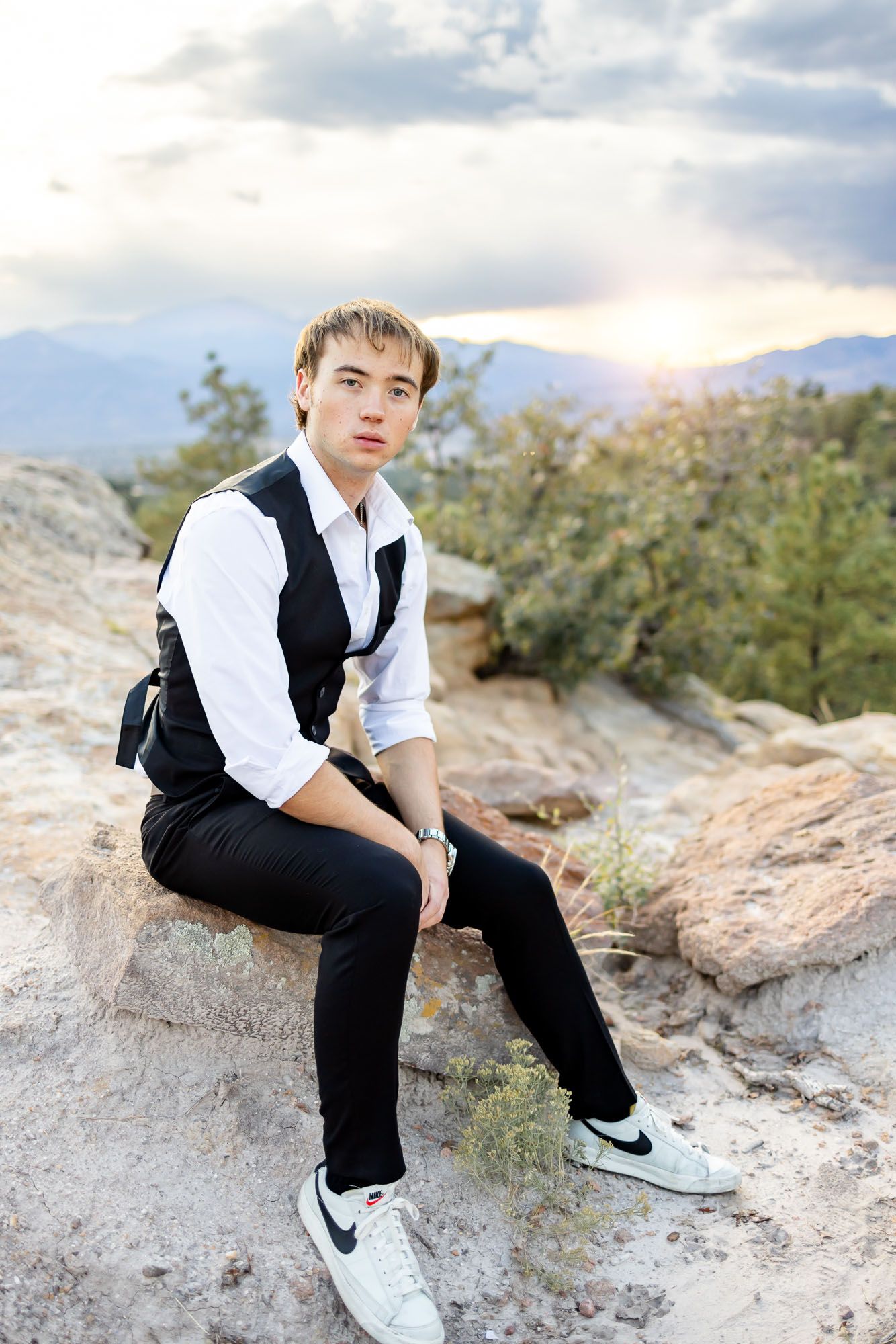 Senior guy sits on the rocks as the sun sets at his senior session at Palmer Park in Colorado Springs.