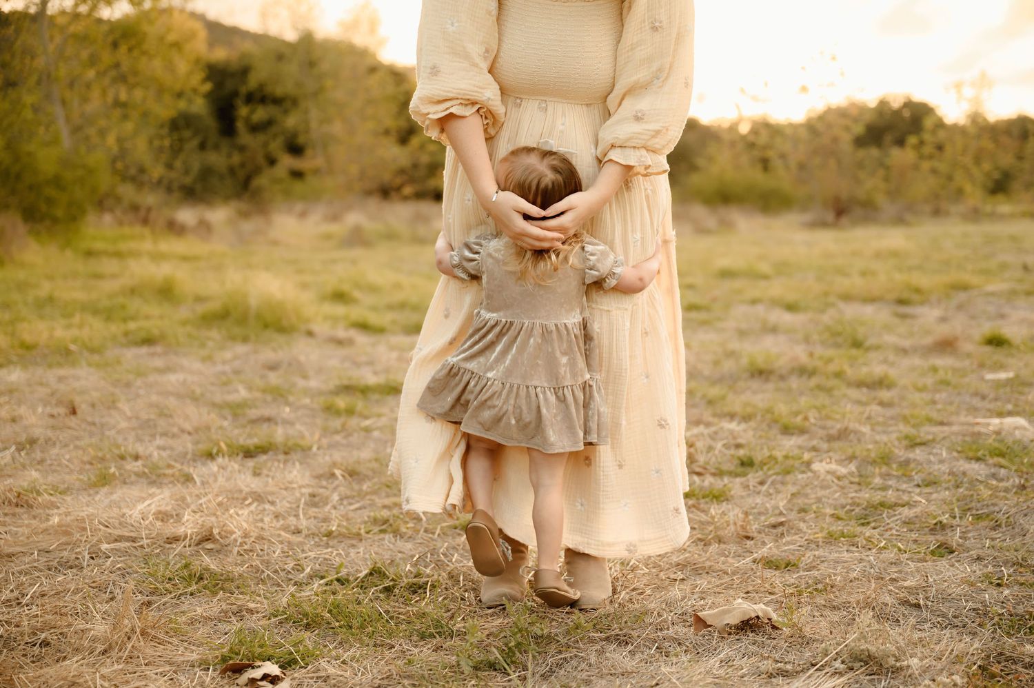 mom embracing toddler girl during golden field mommy & me photoshoot by San Diego photographer, Tiffany Kelterer