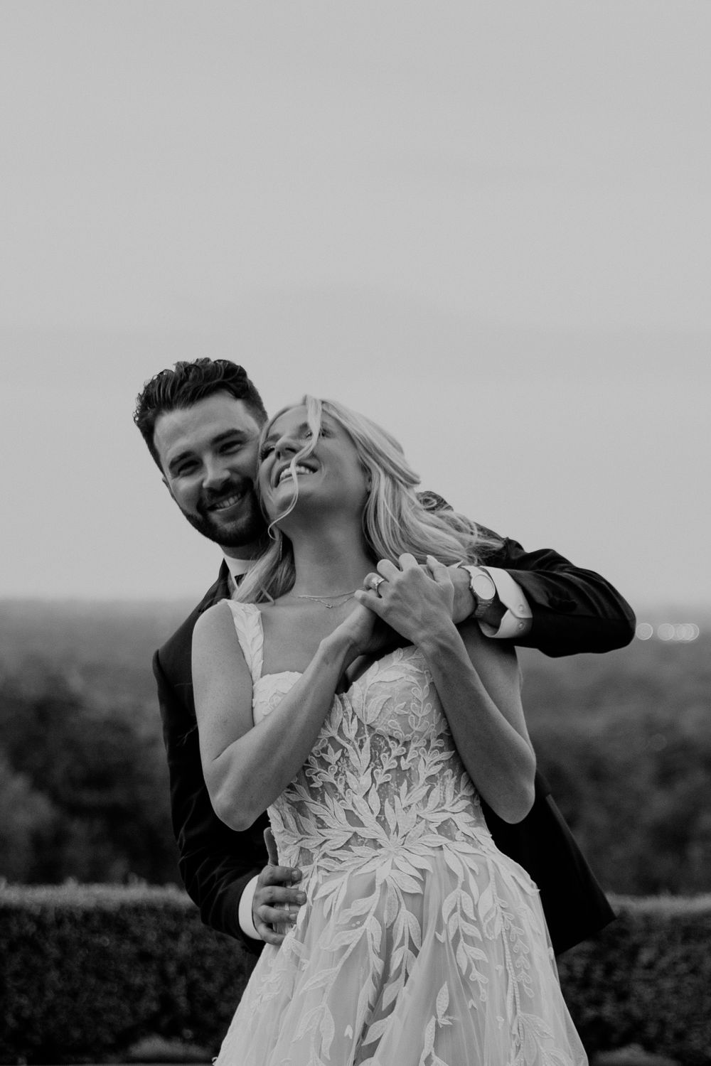 An intimate black and white portrait of a couple sharing a romantic moment outdoors.