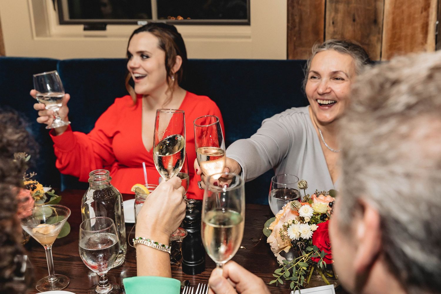 Group of people raising wine glasses in a toast during a dinner celebration.