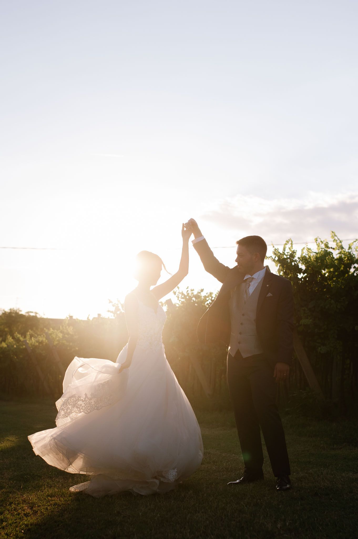 Silhouette of dancing couple against sunset during wedding celebration.