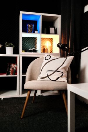 Modern white chair with curved design sits against dark flooring in a minimalist room setting.