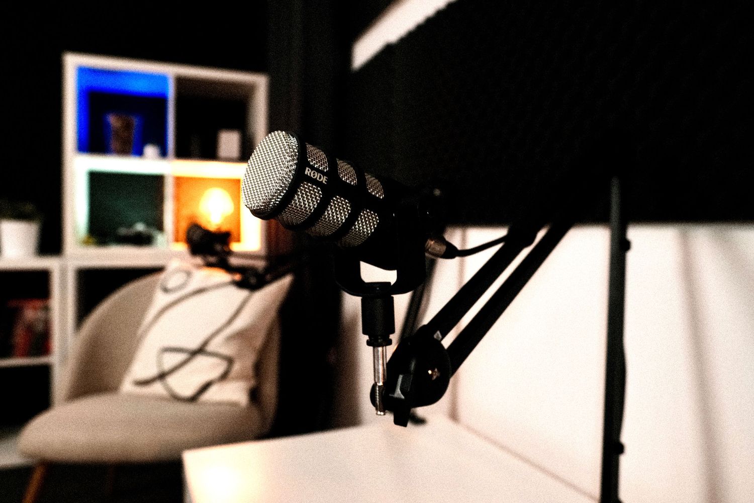 Professional microphone setup with white furniture and ambient lighting in background.